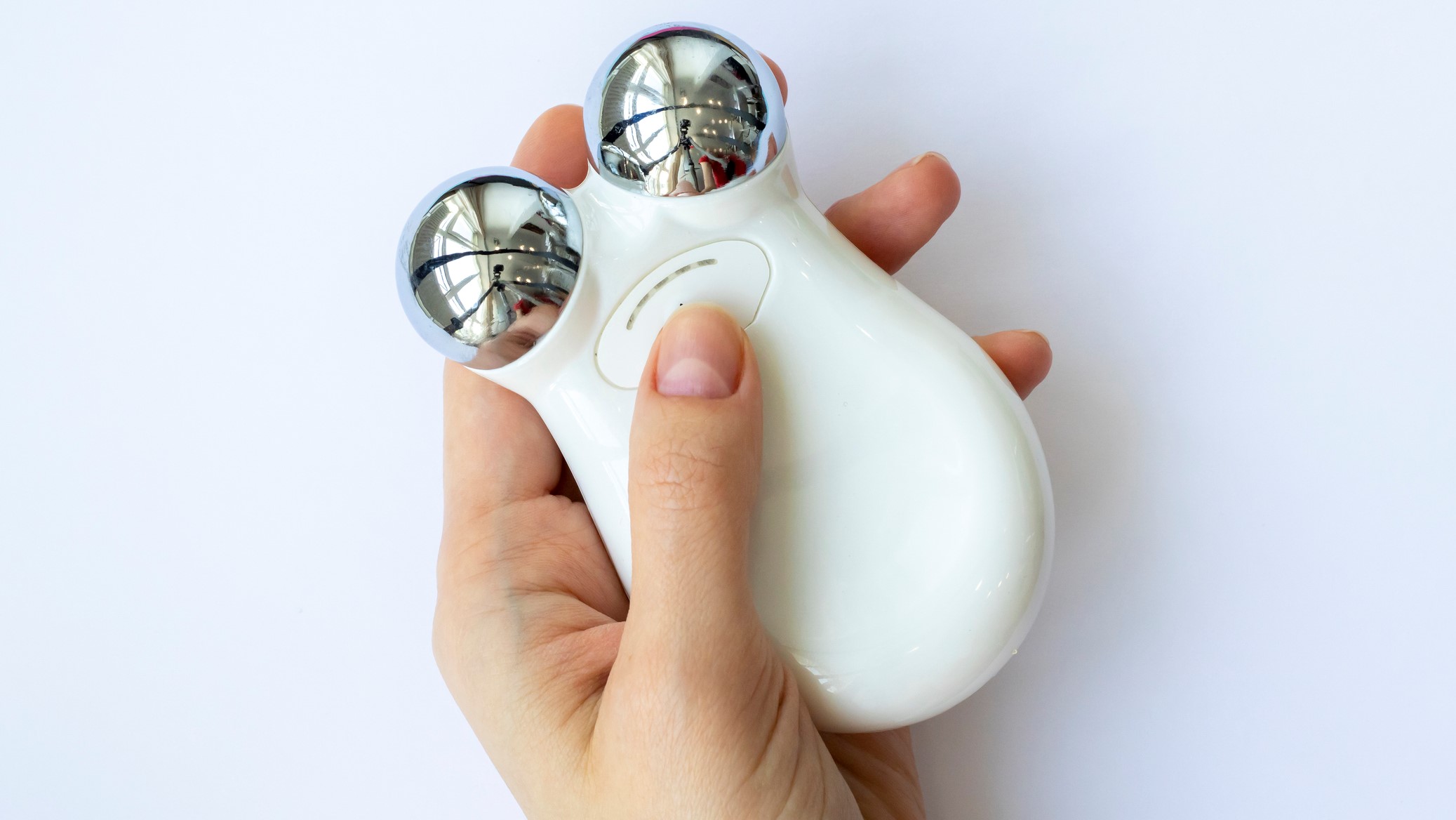 A person holds a microcurrent device for facial toning.