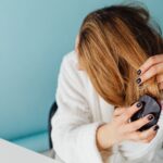 A middle aged woman brushes her hair with a comb.